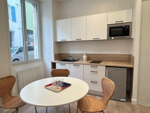 una pequeña cocina con mesa blanca y sillas en Pasteur, appartement fonctionnel en centre-ville, en Lorient