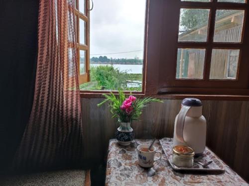 uma mesa com um vaso de flores e uma janela em Flora Cottage , Srinagar em Srinagar