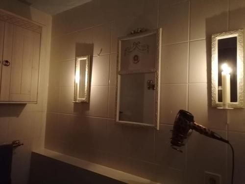 La salle de bains est pourvue d'une lumière sur le mur et d'un miroir. dans l'établissement Romantik Bdsm Apartment Skyview, à Remscheid