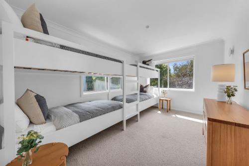 a bedroom with two bunk beds and a desk at A Short time in Merimbula