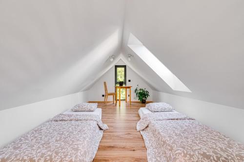 3 camas en una habitación con paredes blancas y una mesa en Gnievo 11 en Międzylesie