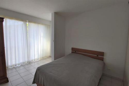 une chambre avec un lit dans une pièce avec des fenêtres dans l'établissement Nouveau dans résidence au calme proche du centre!, à La Grande Motte