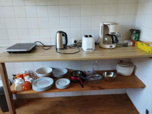 une étagère avec des tasses et des assiettes ainsi qu'une cafetière dans l'établissement MAISON ALBA LA SOURCE, à Mazamet