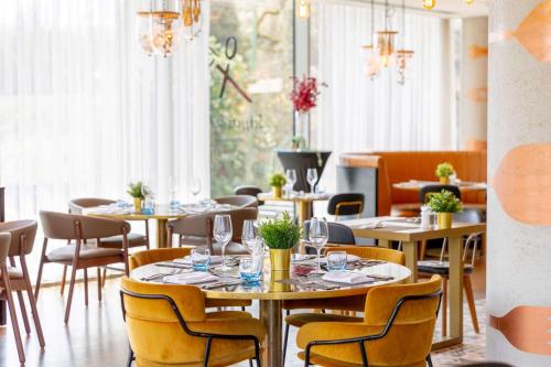 uma sala de jantar com mesas, cadeiras e janelas em Hilton Bournemouth em Bournemouth
