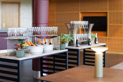 two tables with glasses and potted plants on them at Hilton at St George's Park in Burton upon Trent