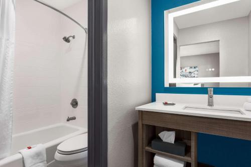 La salle de bains est pourvue d'un lavabo, de toilettes et d'un miroir. dans l'établissement La Quinta Inn by Wyndham Temple, à Temple