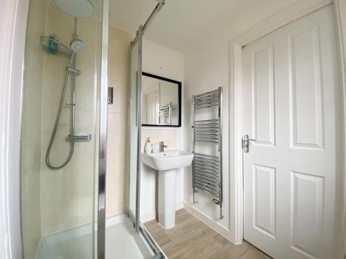 a white bathroom with a sink and a shower at Spacious 4 Bed Peterborough House With Parking in Peterborough