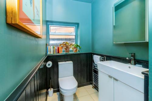 a bathroom with a white toilet and a sink at Fantastic Edwardian 3BR House w/Gdn, Kensal Green in London