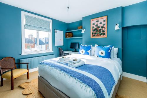 a blue bedroom with a bed with blue walls at Fantastic Edwardian 3BR House w/Gdn, Kensal Green in London