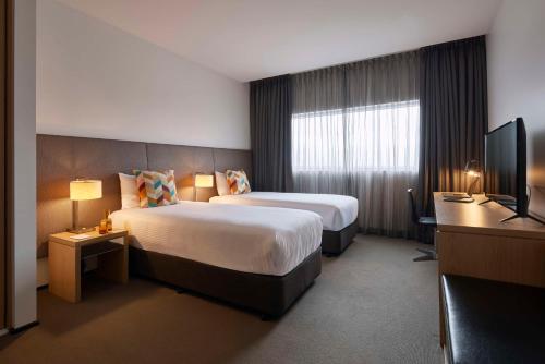 una camera d'albergo con due letti e una televisione di Atura Dandenong a Dandenong