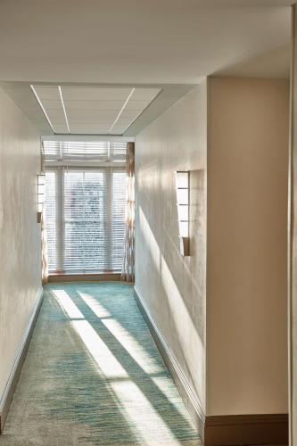 a hallway with a large window and a green rug at The Cotton Sail Hotel Savannah - Tapestry Collection by Hilton in Savannah