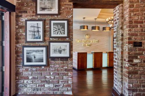 a brick wall with framed pictures on it at The Cotton Sail Hotel Savannah - Tapestry Collection by Hilton in Savannah