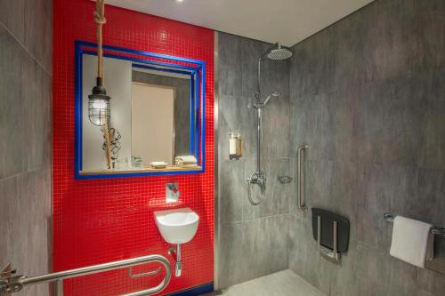 a bathroom with a shower and a red wall at Hampton by Hilton Dubai Al Seef in Dubai