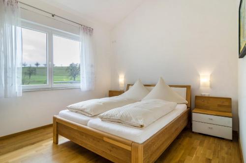 a bedroom with a bed with white sheets and a window at Haus Buche in Hödingen