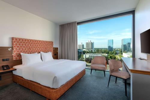 フランクフルト・アム・マインにあるDoubleTree by Hilton Frankfurt Niederradのベッドと大きな窓が備わるホテルルームです。