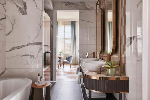 a bathroom with three sinks and a tub and a bath tub at Andaz Prague, By Hyatt in Prague