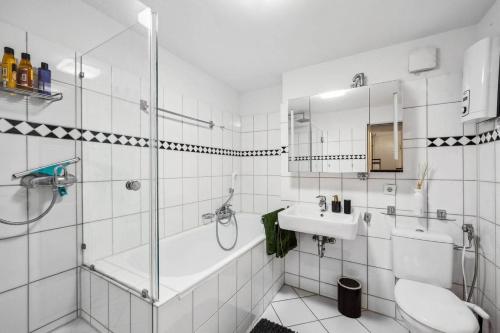 a white bathroom with a shower and a sink at 140 SQM - Dream Flat in Old Town - Trade Fair + Arena in Düsseldorf