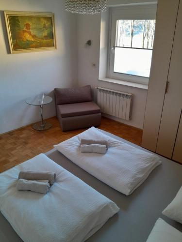 two white beds in a room with a couch at Chalet and Apartment Žonir with SAUNA in Kobarid
