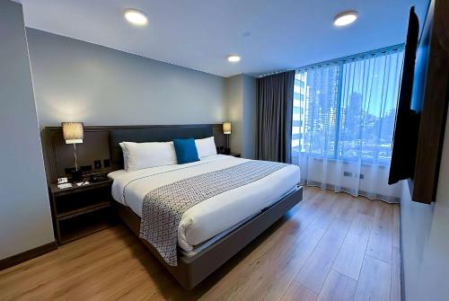 a bedroom with a large bed and a large window at La Quinta by Wyndham Quito in Quito