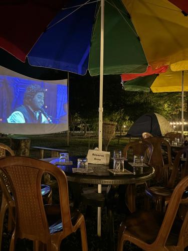 a table with an umbrella in front of a screen at Kodom Bari Retreat, Kaziranga in Kāziranga