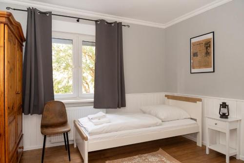 a bed in a room with a window and a chair at Rustic Charm - Cottage by Comfort Housing in Kolonie Neudöberitz