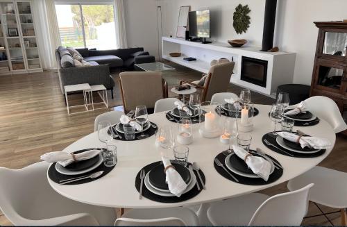 a white dining room table with white chairs and a fireplace at Villa Amêndoa in Loulé