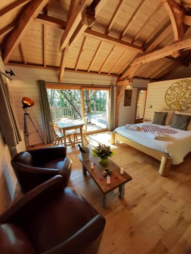 a bedroom with a bed and a couch and a table at Cabanes du Hérisson, cabanes perchées de standing avec spa in Bonlieu