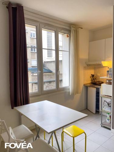 a kitchen with a white table and chairs and a window at Basse in Caen