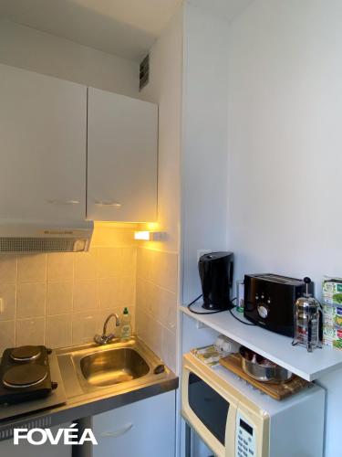 a small kitchen with a sink and a microwave at Basse in Caen