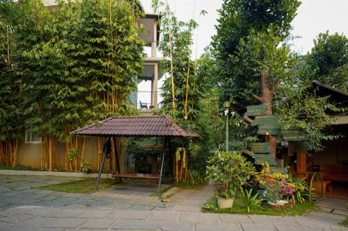 a garden with a gazebo in front of a building at Kuruva Island Resort And Spa - By KABINI BREEZE in Mananthavady