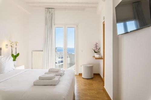 a bedroom with a white bed with towels on it at Azure Bliss Mykonos in Agios Stefanos