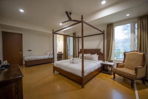 een slaapkamer met een hemelbed en een stoel bij ASHOK VILLA in Jaipur