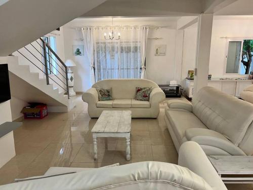 a living room with white furniture and a staircase at Salty Château in Cap Malheureux
