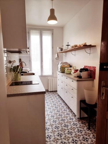 a kitchen with white cabinets and a tile floor at in paris in Villejuif
