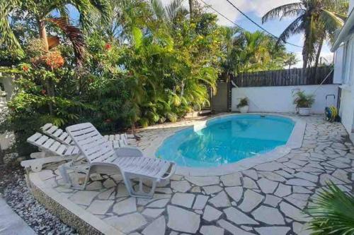 a swimming pool with two white chairs next to a house at Salty Château in Cap Malheureux