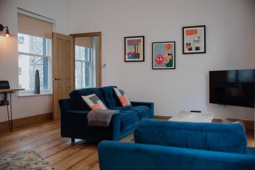 a living room with two blue chairs and a tv at Spacious Norwich Lanes Apartment with Roof Terrace in Norwich