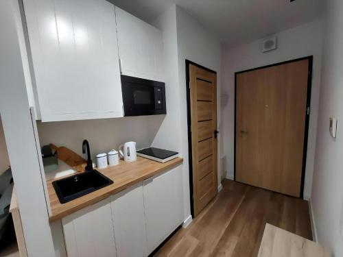 une cuisine avec des placards blancs et un comptoir en bois dans l'établissement L3 Warsaw Apartments Sauna&Gym, à Varsovie