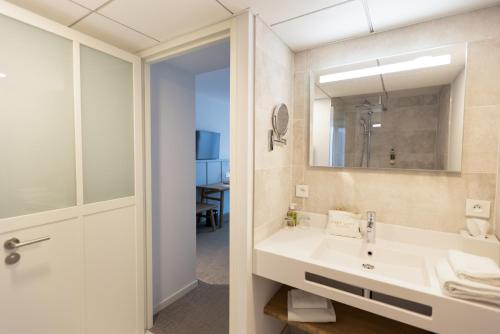 ein Bad mit einem Waschbecken und einem Spiegel in der Unterkunft Éco-Domaine La Fontaine Hotel Spa & Résidence in Pornic