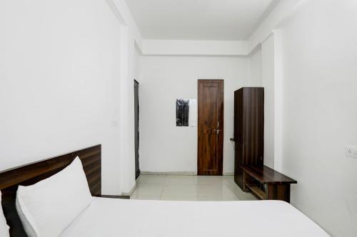 a white bedroom with a bed and a wooden door at OYO Hotel Karthik Palace in Bhopal