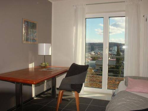 a room with a desk and a bed and a window at Grimm's Lodge in Lörrach