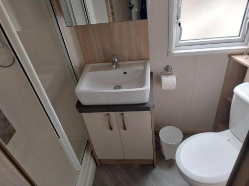 a small bathroom with a sink and a toilet at Bluebell corner - with small enclosed decking in Hastings