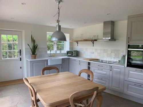 uma cozinha com uma mesa de madeira e uma sala de jantar em Stunning East Devon Cider Barn em Northleigh