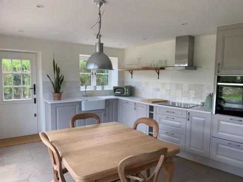 a kitchen with a wooden table and a dining room at Stunning East Devon Cider Barn in Northleigh