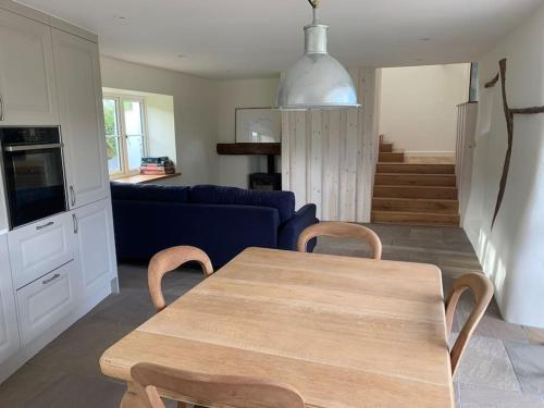 a living room with a table and a blue couch at Stunning East Devon Cider Barn in Northleigh