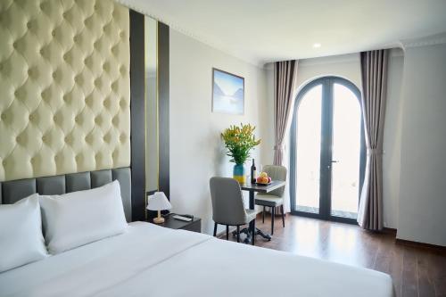 1 dormitorio con 1 cama y escritorio con mesa en Monaco Hotel & Spa Đà Nẵng, en Da Nang