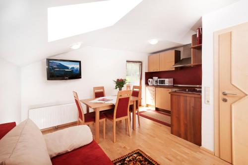 a living room with a dining room table and a kitchen at Haus Hubertus in Fusch an der Glocknerstraße