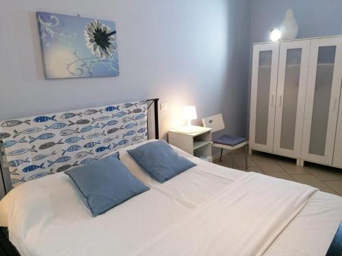 a bedroom with a white bed with two blue pillows at Brezza di Lago in Stresa