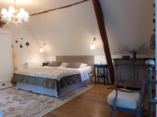 a bedroom with a large bed and a chair at Aux temps d'avant in Gundershoffen