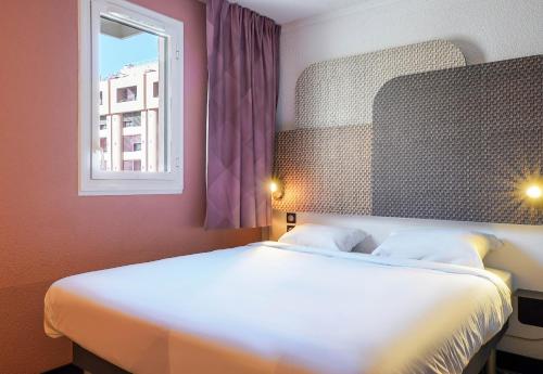 a bedroom with a large white bed with a window at B&B HOTEL Marseille Parc Chanot in Marseille