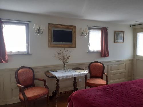 a bedroom with a table and two chairs and a tv at Aux temps d'avant in Gundershoffen